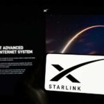 A smartphone displaying the Starlink logo in front of a screen showing a space image