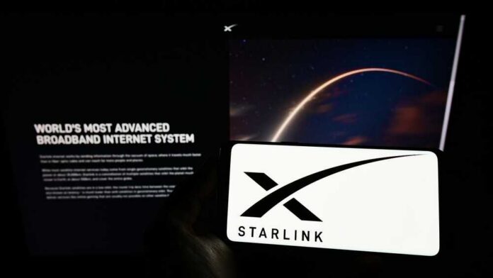 A smartphone displaying the Starlink logo in front of a screen showing a space image