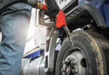 Person fueling a large truck with a gas pump
