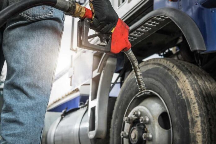 Person fueling a large truck with a gas pump