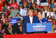 Brutal Crash Hammers Trump Donald Trump at a rally with a woman speaking at the podium; Alexandros Papadiamantis, Margarita Stolbizer, and David Lowy are present in the crowd