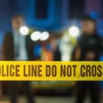 Horrifying: Double Killing Shocker Police tape at a night scene with blurred officers in the background