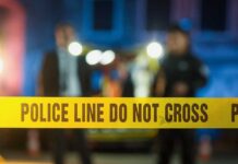 Horrifying: Double Killing Shocker Police tape at a night scene with blurred officers in the background