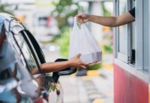 Customer receives a takeout bag at a drive-thru window