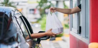 Customer receives a takeout bag at a drive-thru window
