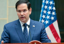 Marco Rubio speaking at a podium with a U.S. flag in the background