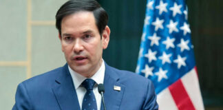 Marco Rubio speaking at a podium with a U.S. flag in the background