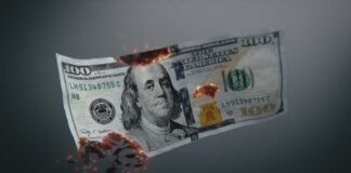Burning US hundred-dollar bill with embers and holes