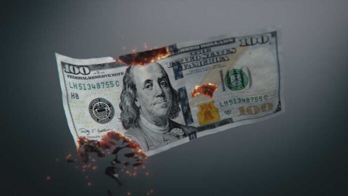 Burning US hundred-dollar bill with embers and holes