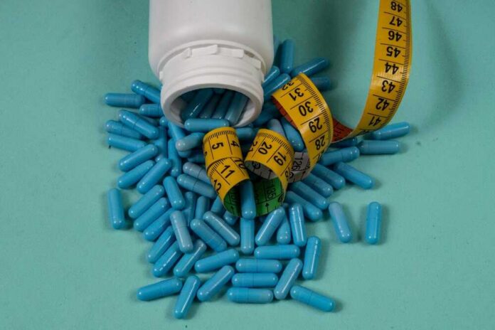 Spilled blue capsules and a measuring tape on a turquoise background