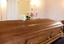 Office Space Icon Gone A wooden casket with a white rose placed on top in a solemn setting